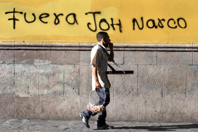 Le 4 août 2019, un homme passe devant un mur sur lequel est inscrit « Dehors JOH [pour Juan Orlando Hernandez] narco », à Tegucigalpa, au Honduras.
