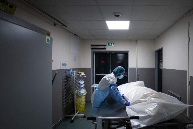 Un membre du personnel médical déplace le corps d’un patient décédé du coronavirus enveloppé dans un sac blanc comme toutes les victimes du Covid-19, le 29 janvier 2021 à l’hôpital Bichat, à Paris.