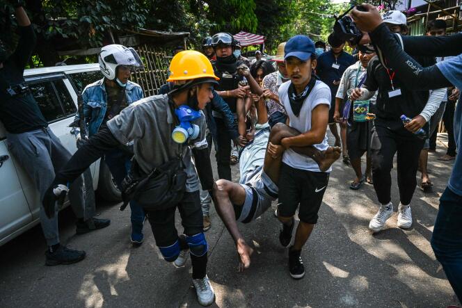 Des manifestants transportent un blessé, le 19 mars 2021, à Rangoun. La répression menée par la junte est de plus en plus violente, incitant de nombreux habitants à quitter le pays.