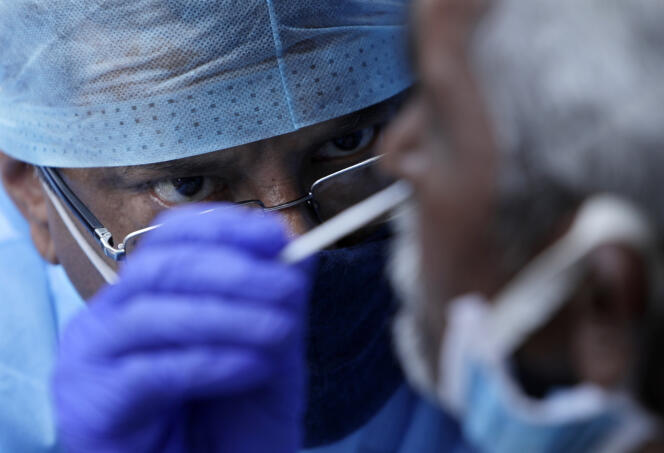 Un agent de santé prélève un échantillon sur écouvillon nasal pour le tester sur un marché de Bombay, en Inde, le jeudi 18 mars 2021.