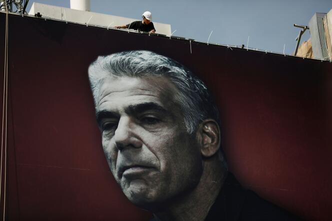 Un homme accroche une affiche de campagne représentant Yaïr Lapid, le chef du parti Yesh Atid, à Tel-Aviv (Israël), le 14 mars.