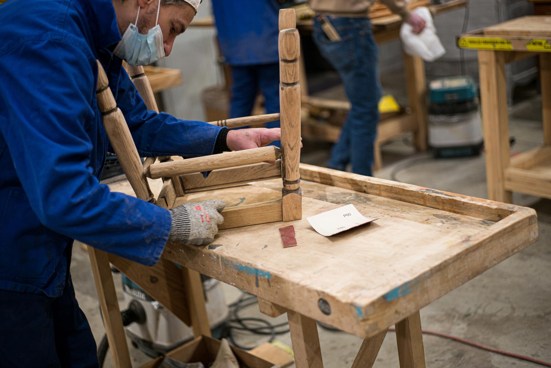 Un détenu ponce une pièce de bois, dans l’atelier de menuiserie géré par l’association Emmaüs.