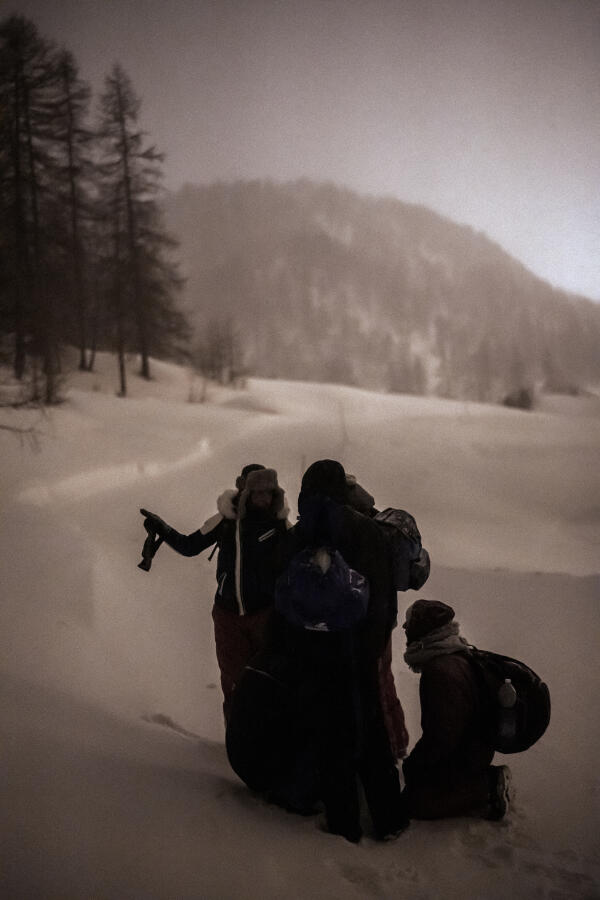 Première pause avant de reprendre la route après une heure de marche. Le groupe d'hommes se concerte sur la direction à prendre et entame une ascension par la montée des pistes de ski du col de Montgenèvre, entre l'Italie et la France, le 14 mars.