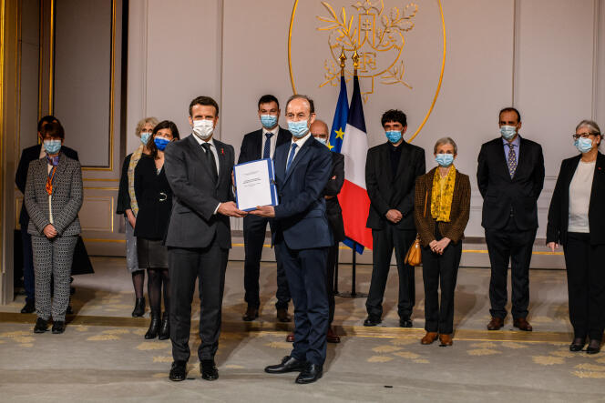 Le président Emmanuel Macron reçoit des mains de l’historien Vincent Duclert, accompagné des membres de la commission Rwanda, le rapport intitulé « La France, le Rwanda et le génocide des Tutsi (1990-1994) », à l’Elysée, le 26 mars 2021.