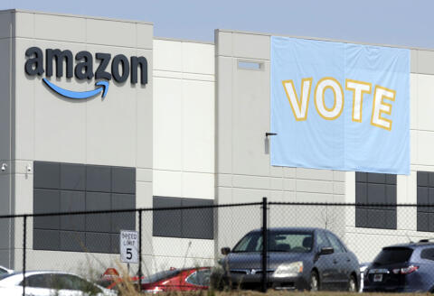 A banner encouraging workers to vote in labor balloting is shown at an Amazon warehouse in Bessemer, Ala., on Tuesday, March 30, 2021. Organizers are pushing for some 6,000 Amazon workers to join the Retail, Wholesale and Department Store Union on the promise it will lead to better working conditions, better pay and more respect. Amazon is pushing back, arguing that it already offers more than twice the minimum wage in Alabama and workers get such benefits as health care, vision and dental insurance without paying union dues. (AP Photo/Jay Reeves)