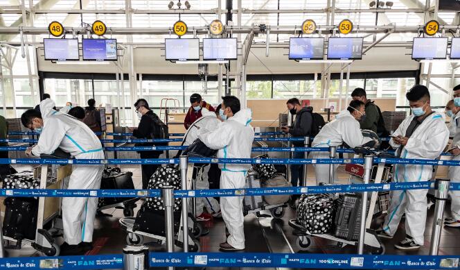Des passagers portant des combinaisons de protection contre le Covid-19 aux guichets de l’aéroport international Arturo-Merino-Benitez de Santiago, le 1er avril, après que le gouvernement a annoncé qu’il fermerait ses frontières pour tout le mois.