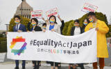 Activists gather in front of parliament before they submit a petition in Tokyo Thursday, March 25, 2021. LGBTQ and other human rights activists submitted a petition with over 106,000 signatures to Japan's ruling party Thursday, calling for an LGBT equality law to be enacted before the Tokyo Games, saying Japan as host nation should live up to the Olympic charter banning gender and sexual discrimination. (Kyodo News via AP)
