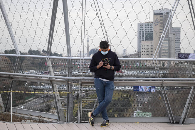 Un Iranien consulte son téléphone sur un pont équipé d’une antenne 5G, dans le parc Ab-o-Atash dans le nord de Téhéran, le 16 février 2021.