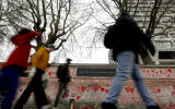 People pass the red hearts on the COVID-19 Memorial Wall mourning those who have died, opposite the Houses of Parliament on the Embankment in London, Wednesday, April 7, 2021. Hearts are being painted onto the wall in memory of the many thousands of people who have died in the UK from coronavirus. (AP Photo/Kirsty Wigglesworth)