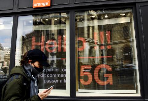A man talks on a mobile phone as he walks past a store of French telecom group Orange advertising the 5G service on its shop window, in Paris on March 19, 2021. (Photo by BERTRAND GUAY / AFP)