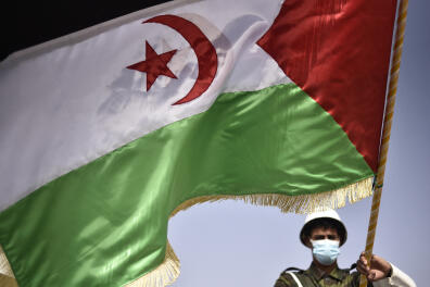 TOPSHOT - A Sahrawi soldier waves the Sahrawi flag during a parade marking the 45th anniversary of the declaration of the Sahrawi Arab Democratic Republic (SDAR), at a refugee camp on the outskirts of the southwestern Algerian city of Tindouf, on February 27, 2021. (Photo by RYAD KRAMDI / AFP)