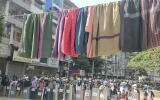 Traditional clothes hang on a rope as protesters holding shields stand in line in the background during a protest against the military coup in Yangon, Myanmar March 6, 2021 in this still image obtained by Reuters from a video.