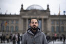 FILE - In this Saturday, Feb. 6, 2021 file photo Tareq Alaows, who is running to become a lawmaker at the German parliament Bundestag poses in front of the Reichstag building in Berlin, Germany. Tareq Alaows who came to Germany as an asylum-seeker in 2015 and launched his campaign to run in Germany's federal election in September for the Green Party said in a statement Tuesday that he had decided to no longer run for parliament for personal reasons. (AP Photo/Markus Schreiber, file)