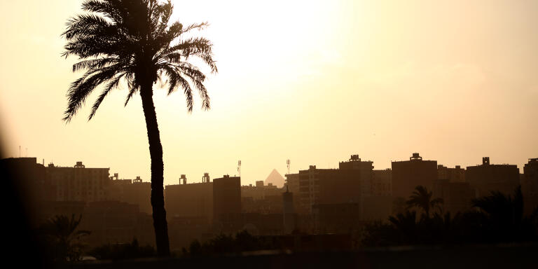 One of the Great Pyramids of Giza is seen through a cluster of residential homes as the sun begins to set over Cairo, Egypt. Photographed on April 9, 2021.