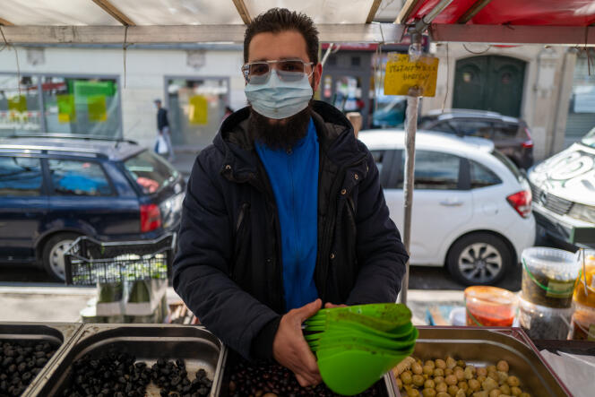 Yahaa Zaoui, 24 ans, tient un stand d’olives et d’herbes aromatiques sur le marché installé boulevard de Belleville à Paris, le 23 avril 2021.