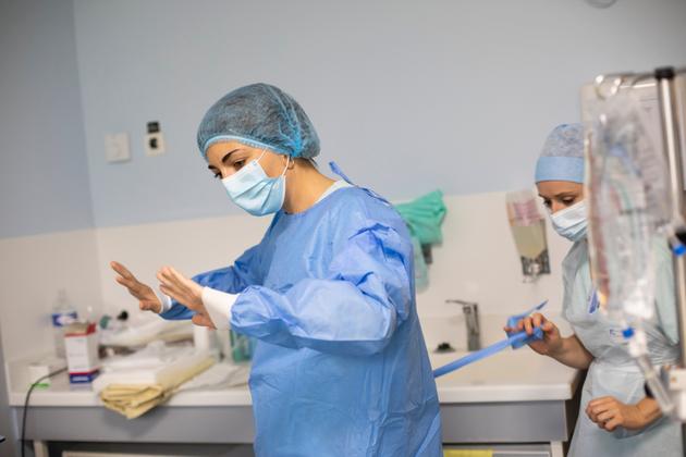 Juliette Patrier, réanimatrice, s’habille en stérile pour pouvoir poser un cathéter sur une patiente non Covid. Service de réanimation de l’hôpital Bichat, à Paris, le 10 avril 2021.