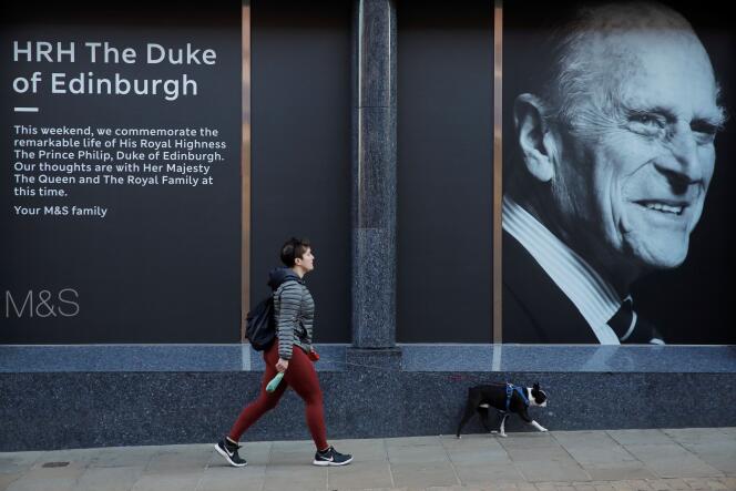 Une femme passe devant un magasin où est affichée une image du prince Philip, époux de la reine Elizabeth II, mort à l’âge de 99 ans, le jour de ses funérailles, à Windsor, près de Londres, le 17 avril.