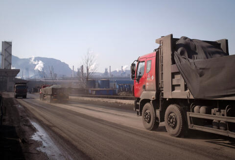 A truck (R) loaded with coal drives towards a steel factory in Tangshan on March 2, 2017. - China said on March 1 it will cut 500,000 jobs in the steel and coal industries this year as it continues to trim excess capacity in the smokestack sectors amid a slowing economy. (Photo by Nicolas ASFOURI / AFP)