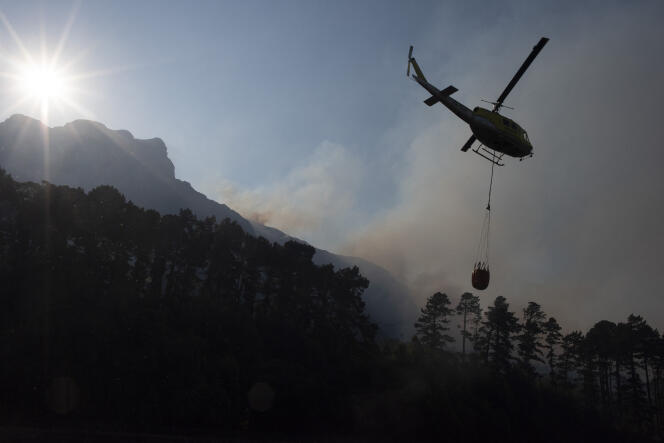 Un hélicoptère participe à la lutte pour éteindre le feu hors de contrôle sur les contreforts de la montagne de la Table, au-dessus de l’université du Cap, le 18 avril 2021.
