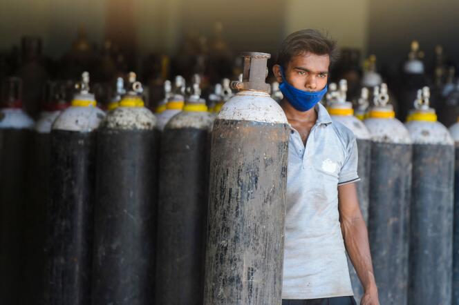 Un travailleur organise des bouteilles d’oxygène médical à destination des hôpitaux, dans la banlieue d’Hyderabad, en Inde, le 23 avril 2021.