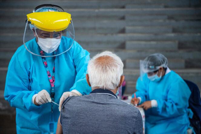 Un agent de santé inocule une dose du vaccin de Pfizer-BioNTech à une personne âgée, dans un centre de vaccination de Lima, le 23 avril 2021.
