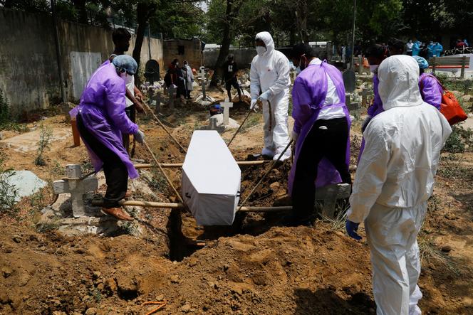Des proches descendent le corps d’une personne morte des suites du Covid  dans une tombe, à New Delhi, en Inde, le 29 avril 2021.