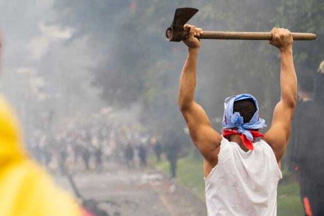 Un manifestant armé d’une hache face à des policiers dans la ville de Popayan, le 14 mai en Colombie.