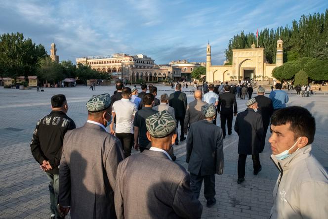 Des Ouïgours se rendent à la mosquée d’Id Kah pour la prière de l’Aïd-el-Fitr, sous l’œil d’un agent de sécurité à Kachgar, le 13 avril.