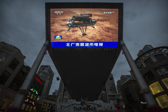 Diffusion par les médias d’État chinois d’une video montrant l’atterrissage tel qu’il se serait passé  du rover Zhurong sur Mars. Grand écran video dans un centre commercial de Pékin, samedi 15 mai 2021.
