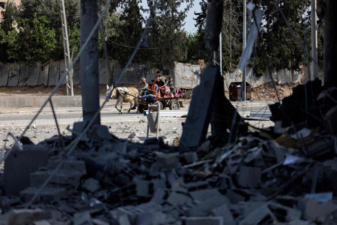 Un bâtiment détruit par une frappe aérienne israélienne à Beit Hanoun, dans le nord de la bande de Gaza. Au loin, une famille palestinienne fuit vers une zone plus sûre, le 14 mai 2021.