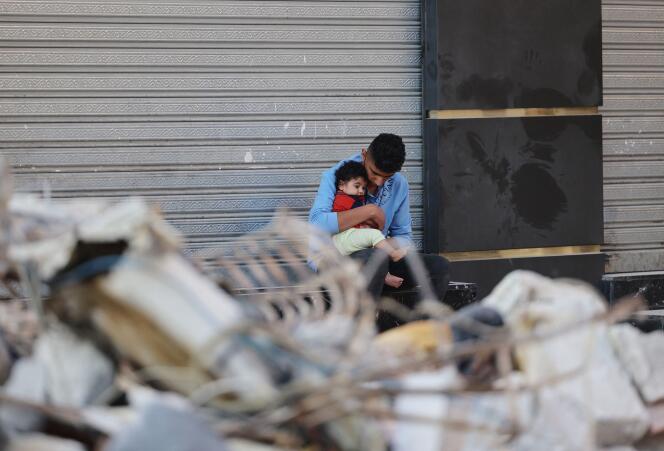 Assis en face de son habitation détruite, un Palestinien serre contre lui son fils, à Gaza, le 16 mai 2021.