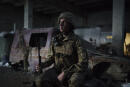 A Ukrainian soldier poses for a photo as he sits in a fighting position on the line of separation from pro-Russian rebels, near Donetsk, Ukraine, Monday, May 3, 2021. (AP Photo/Felipe Dana)