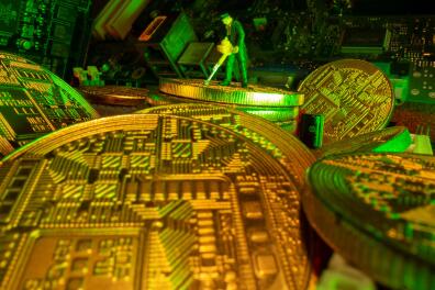 A small toy figure and representations of the virtual currency Bitcoin stand on a motherboard in this picture illustration taken May 20, 2021. REUTERS/Dado Ruvic/Illustration
