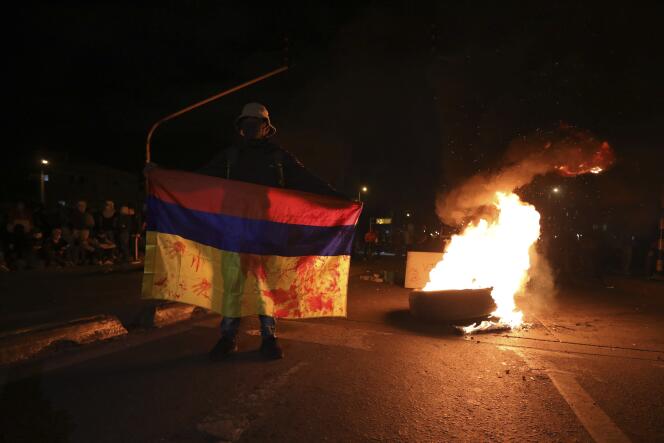 Un manifestant brandit un drapeau colombien près d’une barricade en feu pour protester contre le gouvernement, à Bogota, le 20 mai 2021.