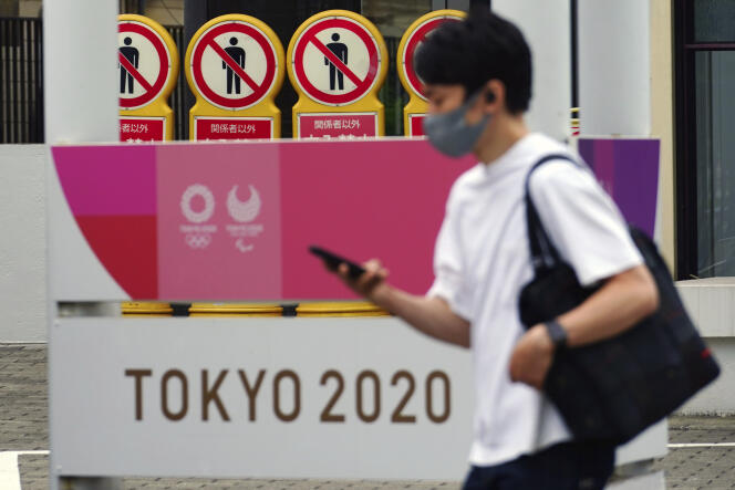 Un homme portant un masque passe devant une affiche des Jeux olympiques de Tokyo, le 11 mai 2021.