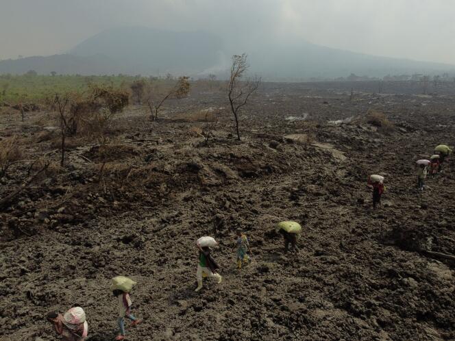 Leurs maisons recouvertes de lave suite à l’éruption du mont Nyiragongo, des gens s’enfuient leurs affaires dans les bras, près de Goma, en RDC, le 25 mai.