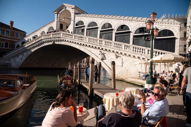 Des touristes sont assis à un café, près du pont Rialto à Venise, en Italie, le 20 mai 2021.