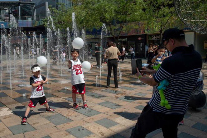 Un homme photographie ses deux fils, au moment où le pouvoir chinois vient d’autoriser aux couples d’avoir un troisième enfant, le 1er juin 2021 à Pékin.