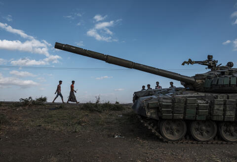 (FILES) In this file photo taken on December 11, 2020 Youngsters walk next to an abandoned tank belonging to Tigrayan forces south of the town of Mehoni, Ethiopia. - US President Joe Biden condemned the six-month conflict in Ethiopia's war-hit Tigray region May 26, 2021 calling for a ceasefire and declaring that human rights abuses "must end." (Photo by EDUARDO SOTERAS / AFP)