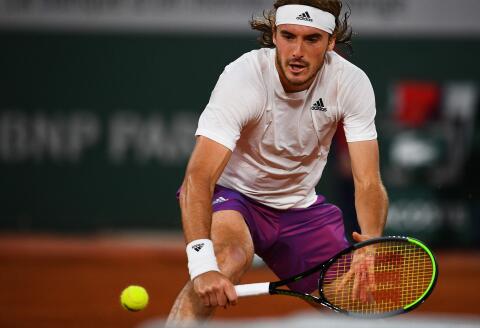 Greece's Stefanos Tsitsipas eyes the ball as he returns it to John Isner of the US during their men's singles third round tennis match on Day 6 of The Roland Garros 2021 French Open tennis tournament in Paris on June 4, 2021. / AFP / Christophe ARCHAMBAULT 