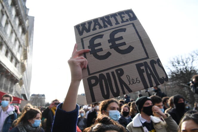 Un étudiant tient une pancarte pour dénoncer la précarité et le manque de moyens des universités françaises, dans une manifestation, à Paris, le 20 janvier.