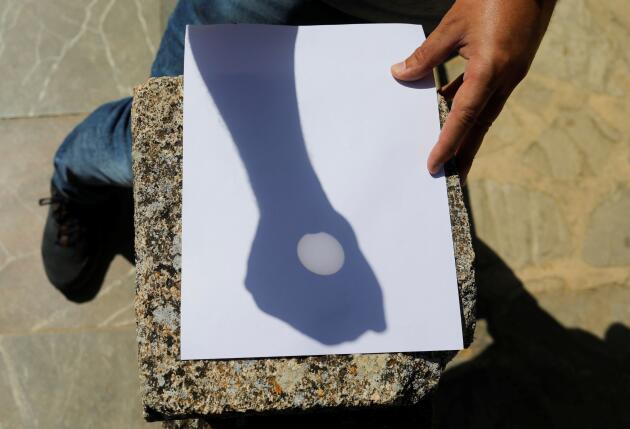 Seorang pria menggunakan teleskop untuk membuat pantulan matahari, menyoroti gerhana sebagian yang terlihat di Ronda, Spanyol pada 10 Juni 2021.