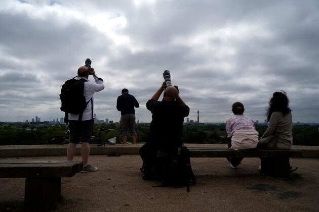 Des personnes tentent de photographier l’éclipse partielle de soleil dans le parc de Primrose Hill à Londres, le 10 juin 2021.
