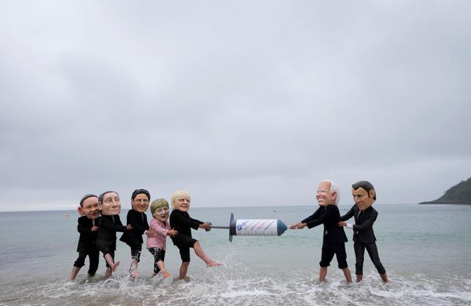 Des militants d’Oxfam simulant au bord de l’eau une bataille autour d’une seringue géante, Oxfam plaidant pour la suspension des brevets, qui permettrait une production en masse des vaccins anti-Covid-19, à Swanpool Beach, à Falmouth, en Cornouailles, le 11 juin 2021.