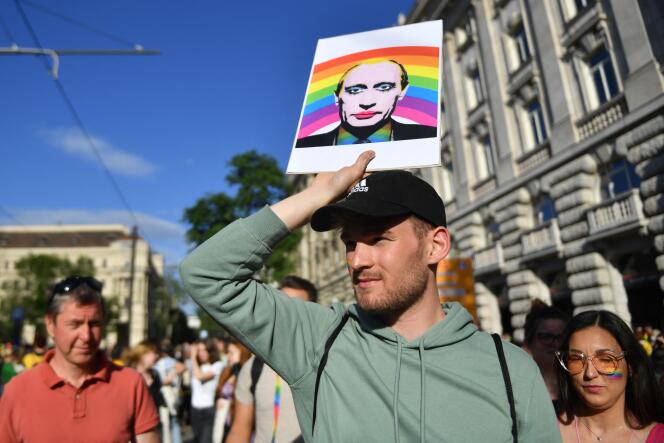 A participant holds a sign bearing the image of Russian President Vladimir Putin, in front of the parliament building in Budapest, June 14, 2021, during a protest against the Hungarian government's bill to ban the 