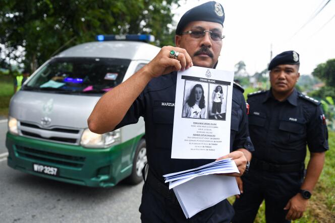 Un agent de la police royale malaisienne montre un avis de recherche avec le portrait de la jeune Franco-Irlandaise de 15 ans disparue, Nora Quoirin, le 9 août 2019.
