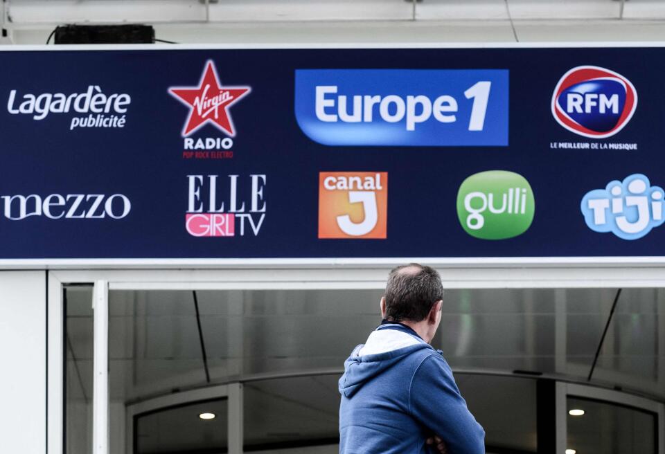 (FILES) In this file photo taken on November 29, 2018 a man stands in front of the building housing French media including Europe 1, Lagardere group, Virgin radio and RFM in Paris. Europe 1 editorial staff goes on strike until June 21, 2021. - / AFP / Philippe LOPEZ