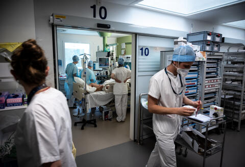 Staff members tend to a patient in the Covid-19 intensive care unit at the Lyon-Sud Hospital in Pierre-Benite, near Lyon, central-eastern France, on April 7, 2021, amid the Covid-19 pandemic. - The Regional Health Agency (ARS) of Auvergne-Rhone-Alpes on April 6 asked all public and private health institutions in the region to forego non-emergency operations to cope with a third wave of Covid-19 patients. (Photo by JEAN-PHILIPPE KSIAZEK / AFP)