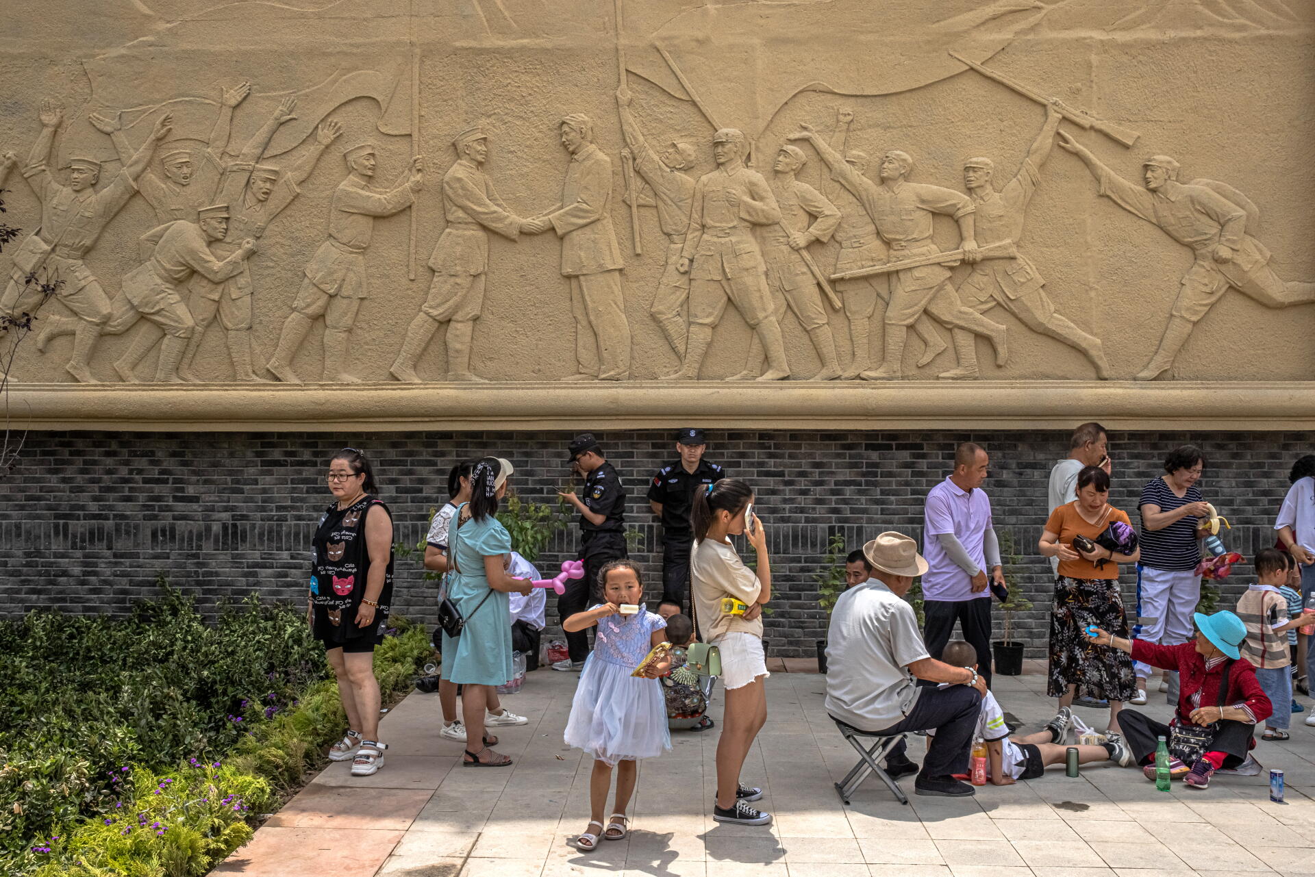 Des passants sous un bas-relief retraçant l’histoire du Parti communiste chinois, à Yan’an (province du Shaanxi), le 12 juin 2021.