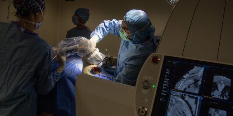 A surgeon uses a Loop-X robotic arm to secure his work on the spine of a patient affected by a metastatic breast cancer, on June 10, 2021 at the University-affiliated hospital (CHU) in Angers, western France.  The Loop-X robotic-assisted surgery installation is a premiere in Europe. / AFP / LOIC VENANCE
